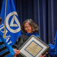 Provost Mili shakes hands with woman after receiving award